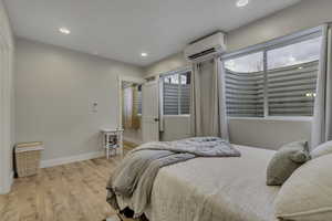 Bedroom featuring light wood finished floors, recessed lighting, and a wall mounted AC