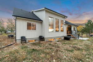 Back of house with board and batten siding and roof with shingles
