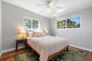 Bedroom with multiple windows, dark wood-style flooring, and ceiling fan