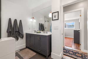 Bathroom featuring dark tile patterned flooring, double vanity, and a shower