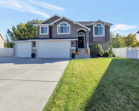 Bi-level home featuring stucco siding, a garage, and concrete driveway with RV parking