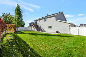 Rear view of property featuring a patio area, a gate (1 of 2), a fully fenced backyard, stairs, and a new Trex deck with black metal railings.