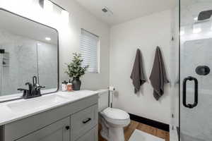 Full bath with a large marble finish shower, vanity, and light wood-style flooring