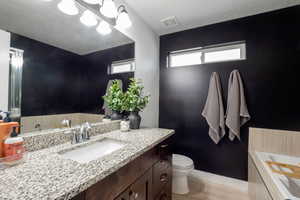 Full main bath with a garden tub and shower, vanity, light wood-style flooring, and a textured ceiling