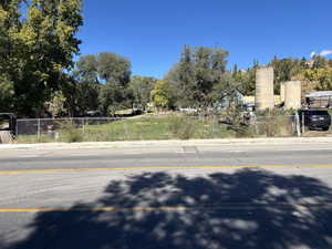 View of asphalt road with curbs, sidewalks, and view of scattered trees