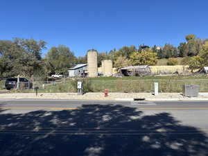 View of asphalt road with view of wooded area and curbs