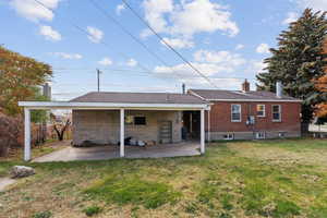 Back of property with a chimney, a yard, and a patio area