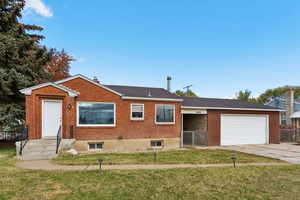 View of front of house featuring a gate, a garage, driveway, and brick siding