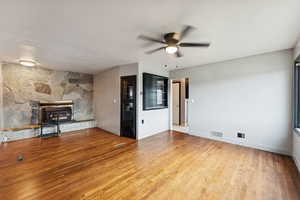 Unfurnished living room with ceiling fan, light wood-style floors, a fireplace, and a textured ceiling