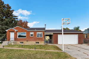 View of front of property featuring a gate, brick siding, concrete driveway, and an attached garage