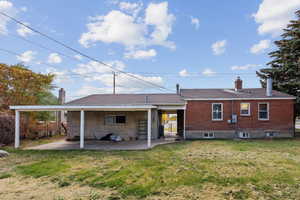 Back of house with a chimney, a patio, and brick siding