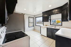 Kitchen featuring white appliances, dark cabinets, light countertops, light tile patterned flooring, and exhaust hood