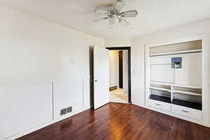 Unfurnished bedroom with hardwood / wood-style flooring, a closet, ceiling fan, a textured ceiling, and a decorative wall