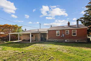 Rear view of house featuring a chimney, a yard, a patio, and brick siding