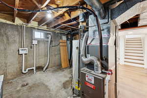 Below grade area featuring stairs, heating unit, and gas water heater