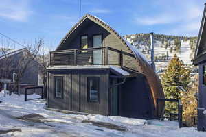 Snow covered property featuring a balcony and a gambrel roof