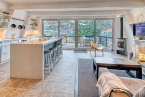 Kitchen featuring beamed ceiling, a kitchen breakfast bar, open shelves, a wood stove, and white cabinets