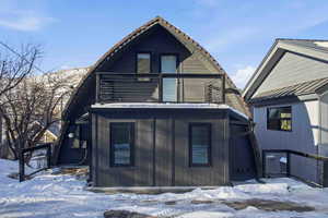 Snow covered back of property featuring a balcony