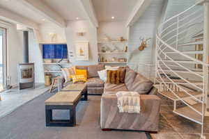 Tiled living room featuring a wood stove, beamed ceiling, recessed lighting, and wooden walls