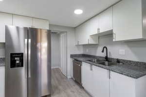 Kitchen featuring appliances with stainless steel finishes, light wood-style flooring, and white cabinets
