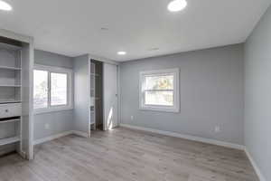 Unfurnished bedroom 1 with light wood-style flooring, recessed lighting, and two closets