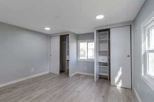 Unfurnished bedroom 1 with multiple closets, light wood-style floors, and recessed lighting