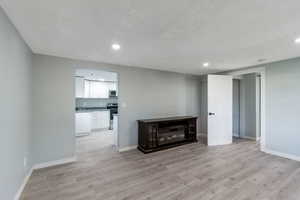 Unfurnished living room featuring light wood-style floors, a glass covered fireplace, and recessed lighting