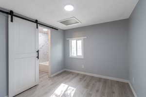 Master bedroom featuring light wood-type flooring and a master bath with a barn door