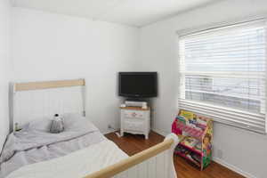 Bedroom with dark wood-type flooring and baseboards