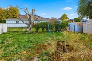 View of yard featuring a storage shed, a playground, and a mountain view
