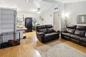 Living area with light wood-type flooring, a ceiling fan, vaulted ceiling, and crown molding