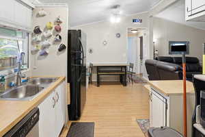 Kitchen featuring light countertops, white cabinetry, lofted ceiling, freestanding refrigerator, and open floor plan