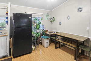 Kitchen featuring freestanding refrigerator, light wood-type flooring, crown molding, and healthy amount of natural light