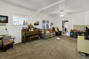 Carpeted living area with healthy amount of natural light, ceiling fan, and arched walkways