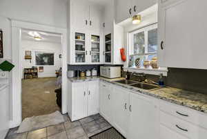 Kitchen featuring white cabinetry, light colored carpet, light stone countertops, and white microwave