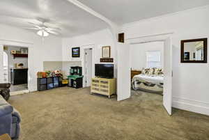Living area featuring carpet floors, arched walkways, and ceiling fan
