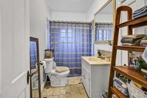 Full bathroom with light tile patterned floors, vanity, and a shower with shower curtain