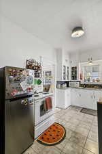 Kitchen with white cabinetry, white appliances, and light tile patterned flooring