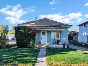 Bungalow-style home featuring roof with shingles, covered porch, and stucco siding