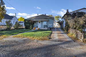 View of front of house featuring a shingled roof, stucco siding, covered porch, and a chimney