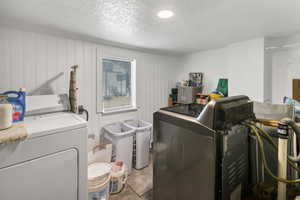 Laundry room featuring independent washer and dryer, a textured ceiling, and light tile patterned flooring