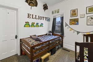 Carpeted bedroom featuring crown molding and baseboards