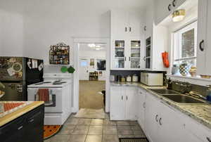 Kitchen featuring white cabinetry, white appliances, light colored carpet, and glass insert cabinets