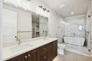 Bathroom with double vanity, a walk in closet, light tile patterned flooring, a marble finish shower, and a soaking tub