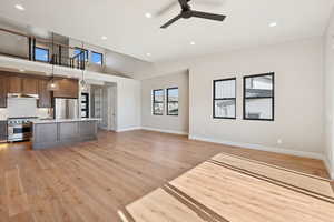 Unfurnished living room with recessed lighting, ceiling fan, light wood-type flooring, and a high ceiling