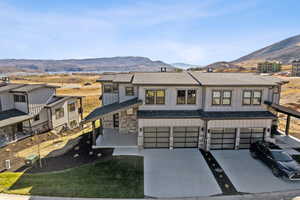 Modern farmhouse style home featuring stone siding, a mountain view, board and batten siding, roof with shingles, and driveway