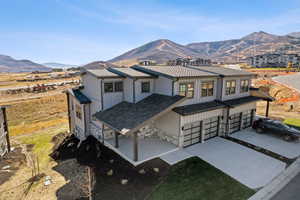 Modern farmhouse featuring stone siding, a mountain view, driveway, covered porch, and board and batten siding