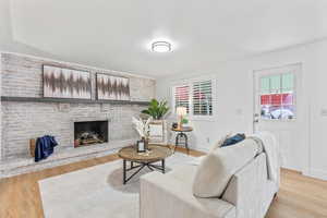 Living area featuring LVP floors, exterior exit and a brick fireplace