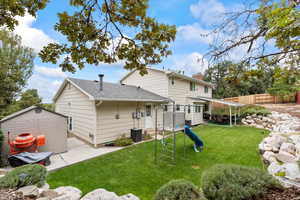 Rear view of property featuring a playground, a fenced backyard, and storage shed