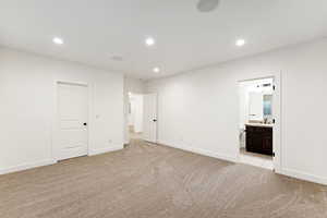 Unfurnished bedroom with light carpet, recessed lighting, and connected bathroom